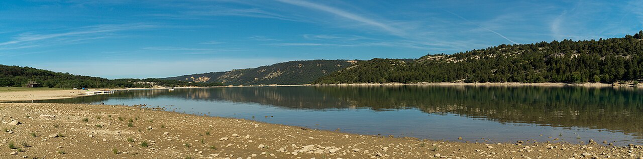 Panorama van Lac de Sainte-Croix met een stenige oever en beboste heuvels